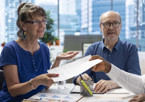 Financial advisor giving the retirement plan documents to old people, securing a contract with life insurance policy. Broker counseling clients to choose a suitable pension option.